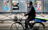 Un cycliste passe devant un panneau électoral avec les candidats à la mairie de Paris, le 7 mars 2026, à Paris