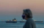 Une promeneuse devant l'océan à Long Beach, alors que passent des pétroloiers au large, le 25 avril 2020