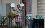 Une habitante de Rome participe à un concert improvisé depuis son balcon, utilisant des couvercles de casseroles comme cymbales, le 13 mars 2020