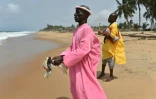 Un croyant tient deux pigeons et avance en direction de la mer, lors d'une prière sur la plage de Grand-Bassam en Côte d'Ivoire, le 1er avril 2016