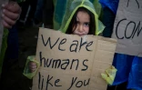 Une petite fille tient une pancarte pendant une manifestation de migrants pour la réouverture de la frontière gréco-macédonienne