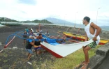 Des pêcheurs et des habitants déplacent un bateau en bois en lieu plus sûr, en prévision de l'arrivée du super typhon Man-yi, à Legaspi, capitale de la province d'Albay, au sud-est de Manille, le 16 novembre 2024