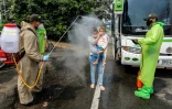 Des membres de la police nationale désinfectent des Vénézuéliens retournant au pays depuis la Colombie, le 4 avril 2020 sur le pont international Simon Bolivar, à Cucuta