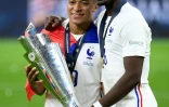 L'attaquant français Kylian Mbappé (g) et le milieu de terrain français Paul Pogba posent avec le trophée à la fin de la finale de la Ligue des Nations de football entre l'Espagne et la France au stade San Siro de Milan, le 10 octobre 2021.