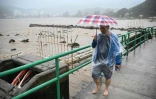 Un homme marche sur un pont au-dessus d'une rivière en crue sur l'île de Lantau à Hong Kong, le 8 septembre 2023