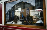 Une femme regarde à travers la vitre du tramway où se reflète une affiche électorale du Premier ministre turc le 30 octobre 2015 à Istanbul
