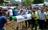 Des musulmans bosniaques mettent en terre des cercueils contenant les restes de victimes du massacre de Srebrenica en 1995, dans le mémorial de Potocari le 11 juillet 2021