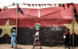 Des femmes passent devant les drapeaux du Mouvement populaire de libération de l'Angola (MPLA) à Luanda, le 23 août 2022