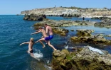Des adolescents sautent d'un rocher dans la mer, le 16 juillet 2022 à Sébastopol, en Crimée