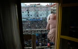 Une femme regarde se tient sur un balcon d'où elle regarde un rassemblement à la méoire d'un vendeur de rues sénégalais, sur la place Nelson Mandela, le 16 mars 2018