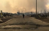 Photo fournie par les autorités canadiennes montrant, le 5 mai 2016 un policier marchant dans une rue de Fort McMurray où de nombreuses habitations ont été ravagées par des incendies