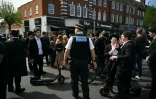 Un officier de la Metropolitan Police demande à des membres de la communauté juive de s'éloigner d'un cordon à l'angle de Golders Green Road et Beverley Gardens, dans le quartier de Golders Green, au nord de Londres, le 29 avril 2026