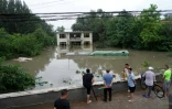 Des personnes regardent un bâtiment partiellement submergé dans une zone inondée, après de fortes pluies dans le district de Fangshan à Pékin, le 31 juillet 2023