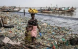 Une femme marche avec sa petite fille le long de la baie de Hann à Dakar, au milieu des déchets qui recouvrent le sable. Photo prise le 29 septembre 2023
