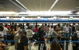Des voyageurs font la queue à un comptoir d'enregistrement à l'aéroport de Miami, pendant une panne informatique mondiale, le 19 juillet 2024 en Floride
