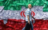 Un homme passe devant un drapeau iranien installé le long de la route à Téhéran le 29 avril 2026