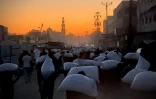 Des Palestiniens marchent en portant des sacs de farine à Khan Younès, dans le sud de la bande de Gaza, le 22 juillet 2025