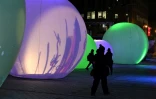 Des passants découvrent les sphères lumineuses de "Nouvelle Lune", pendant le festival de "Luminothérapie", le 14 décembre 2020 à Montréal