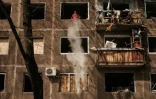 Un homme nettoie les débris d'une fenêtre brisée dans un appartement d'un immeuble endommagé par les frappes russes, à Kramatorsk, dans l'est de l'Ukraine, le 5 mai 2022
