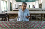 La créatrice Brigitte Singh inspecte une étoffe imprimée à la planche dans son atelier à Amber, le 2 juin 2022 dans l'Etat du Rajasthan, en Inde