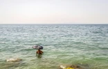 Une baigneuse s'est munie d'un parapluie pour se protéger du soleil sur la plage d'Alimos près d'Athènes, le 15 juillet 2023