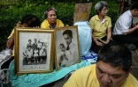 Des Thaïlandais apportent des photos de la famille royale, et prient devant l'hôpital où est soigné le roi à Bangkok, le 13 octobre 2016