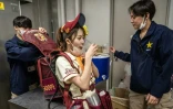 Des assistants changent le fût de la vendeuse de bière Mariko Matsumoto pendant un match de baseball à Tokyo, le 28 avril 2023