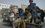 Des combattants talibans armés escortent des Afghanes en niqabs noirs lors d'un rassemblement pro-talibans devant l'Université Shaheed Rabbani, le 11 septembre 2021 à Kaboul