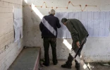Deux hommes consultent les listes électorales dans un bureau de vote lors des élections municipales du village de Qabatiyah, au sud de Jénine, en Cisjordanie occupée par Israël, le 25 avril 2026