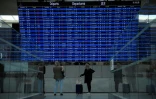 Photo prise le 16 septembre 2022 montrant des voyageurs cherchant des informations sur leur vol à l'aéroport Roissy-Charles de Gaulle