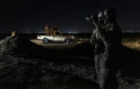 Des garde-côtes mauritaniens  utilisent des jumelles de vision nocturne pour surveiller les activités le long du littoral, tandis que d'autres se tiennent à l'arrière d'une camionnette à Nouadhibou (Mauritanie), le 23 avril 2026