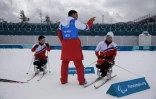 Les Nord-Coréens Ma Yu Chol (d) et Kim Jong Hyon (d) écoutent les conseils de leur entraîneurs de ski nordique aux Jeux Paralympiques, le 9 mars 2018 à Pyeongchang   