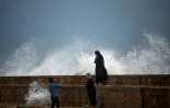 Des passants se prennent en photo devant les vagues, sur une plage de Karachi, au Pakistan, le 13 juin 2023