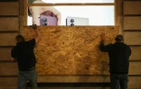 Des personnes installent un panneau en bois pour protéger une boutique de téléphonie, le 23 octobre 2026 à Paris