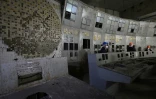 Des représentants de Greenpeace et des journalistes en combinaisons de protection se rendent dans la salle de contrôle du quatrième bloc détruit de la centrale nucléaire de Tchernobyl, le 9 avril 2026 en Ukraine