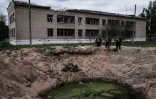 Le cratère laissé par l'explosion d'une bombe près de l'école de Novomykolaïvka, dans l'est de l'Ukraine, le 11 mai 2022

