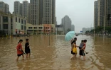 Des habitants dans une rue inondée de  Zhengzhou, le 23 juillet 2021 en Chine