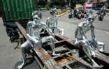 Les artistes de rue Keris Munandar (d), son frère Ari Munandar (g) et leur voisin Riyan Ahmad Fazriyansah assis sur la remorque d'un camion porte-conteneurs à Jakarta, le 7 avril 2025 en Indonésie