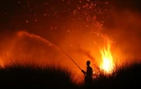 Photo prise le 11 août 2026 d'un villageois arrosant la végétation lors d'un incendie à Palangkaraya, dans le Kalimantan en Indonésie