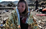 Une femme tient son enfant enveloppé dans une couverture de survie, après son arrivée sur l'île grecque de Lesbos le 27 octobre 2015
