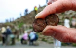 Cliff Henry, du National Trust, montre des pièces de monnaie rouillées laissées par les touristes sur le site de la Chaussée des Géants près de Bushmills en Irlande du Nord, le 8 juillet 2025
