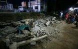 Des policiers près des décombres d'un mur effondré à Mati, sur l'île méridionale de Mindanao, le 10 octobre 2025, après un tremblement de terre qui a frappé les Philippines