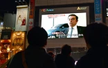 Des passants regardent le 22 novembre 2018 à Tokyo la photo de Carlos Ghosn, patron de Renault-Nissan, arrêté pour soupçons de malversations financières et fraude fiscale
