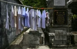 Des vêtements sèchent sur un étendoir posé entre une tombe et un mur au cimetière nord de Manille, aux Philippines, le 21 octobre 2025