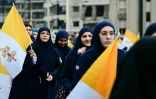 Des femmes musulmanes libanaises tiennent des drapeaux du Vatican en attendant l'arrivée du pape Léon XIV dans la banlieue sud de Beyrouth, un quartier résidentiel connu sous le nom de Dahiyeh, bastion du Hezbollah, le 30 novembre 2025 au Liban
