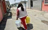 Une femme porte des sceaux remplis d'eau à Mexico, le 19 avril 2017