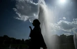 Une personne tient un éventail en passant devant une fontaine, le 22 juin 2026 à Paris