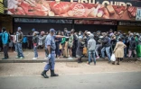 Un policier intime l'ordre aux personnes qui font la queue devant un supermarché de respecter les règles de distanciation sociale, le 28 mars 2020 à Yeoville, dans le centre de Johannesburg, en Afrique du Sud 