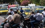 Un homme tient un ventilateur alors qu'il se déplace à moto dans une rue de Téhéran, pendant une vague de chaleur en Iran, le 22 juillet 2025