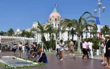 Des passants se recueillent sur la Promenade des Anglais, près des fleurs déposées en hommage aux victimes de l'attentat de Nice, le 14 juillet 2017, un an après l'attaque